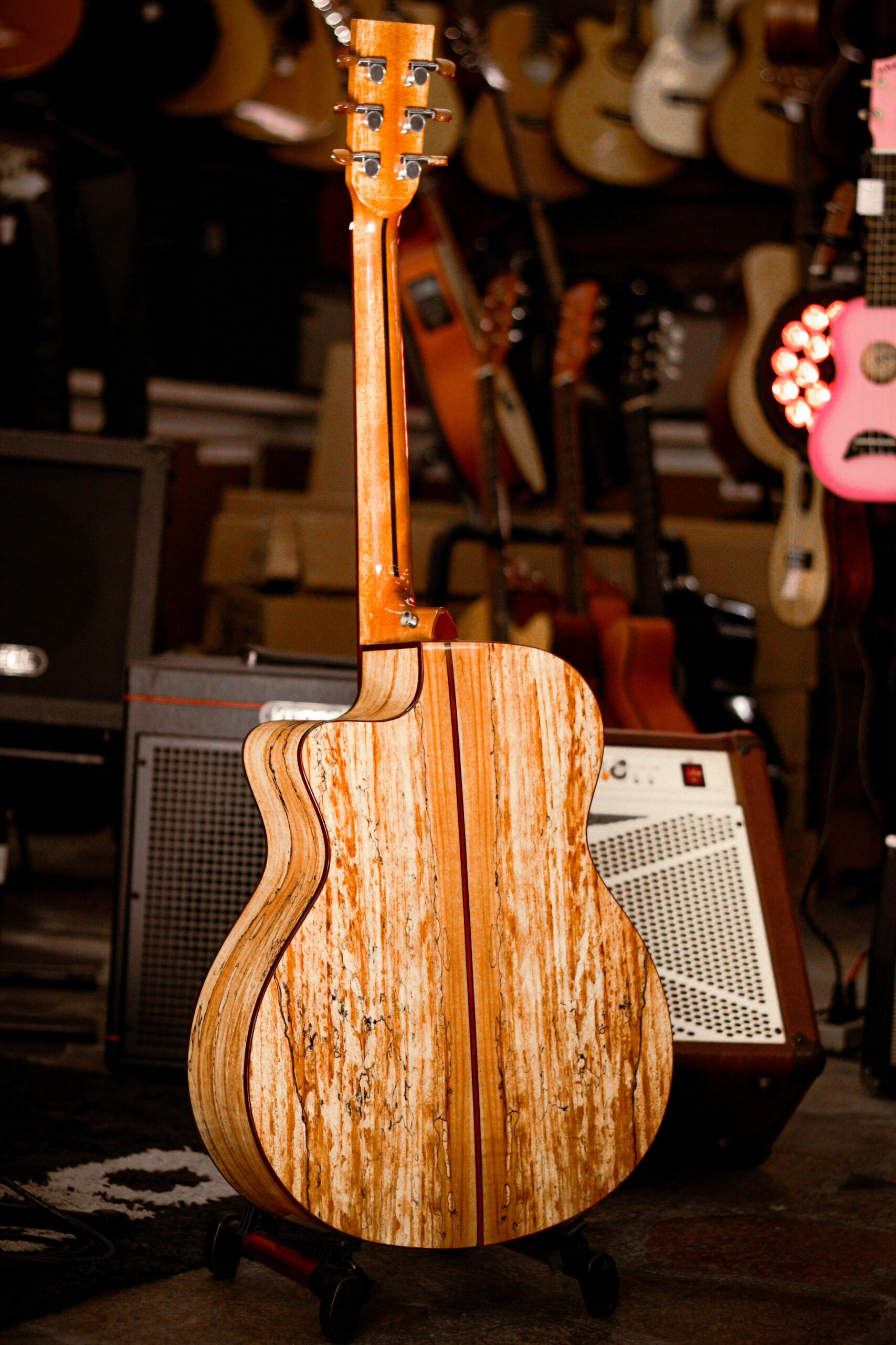 Back view of a wooden acoustic guitar displayed in a cozy music store.